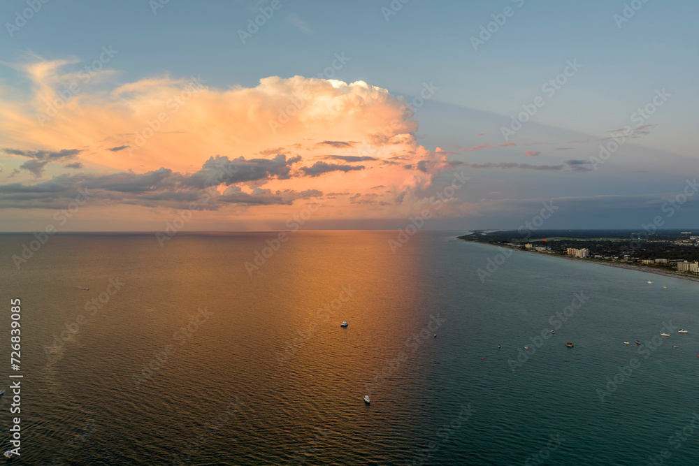 Aerial view of small yachts at sunset floating on sea waves with ripple surface. Motor boats recreation on ocean surface