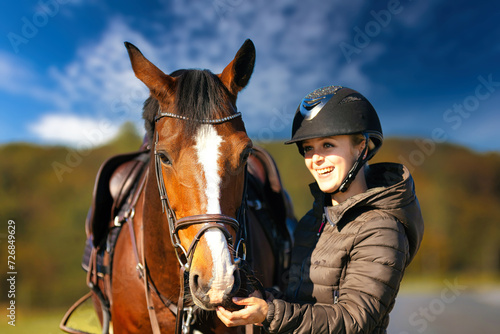 Horse head portraits in front of a blue sky and a rider standing next to it.. © RD-Fotografie