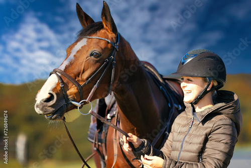 Horse head portraits in front of a blue sky and a rider standing next to it.. © RD-Fotografie