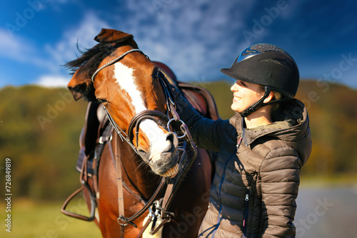 Horse head portraits in front of a blue sky and a rider standing next to it..
