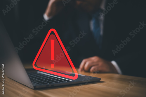 Hacker or programmer using laptop with triangle caution warning sign, coding, cryptography, hacker, crime, virus, for notification error and maintenance concept. Computer with red warning sign. photo