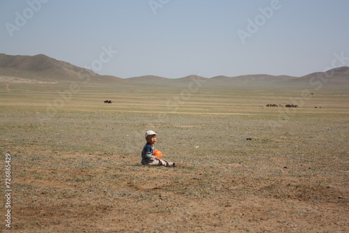 A boy with his only ball is in the lonesome steppe of Atar valley, Tuv province, Mongolia. The surrounding steppe is so vast and silent all year around. It is windy and cold any time there. 