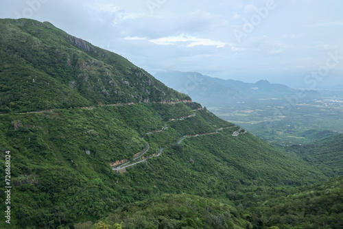 Long winding mountain road leading through rural countryside in Munnar Kerala India. Mountain highway with sharp hairpin turns on a fogy rainy day. Dangerous road to drive accident prone.