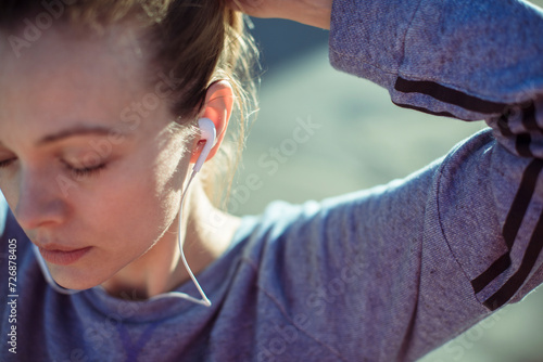Young athletic woman tying her hair before exercising in the city