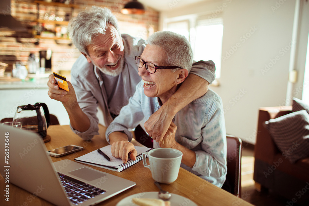 Senior couple online shopping with their credit card at home Senior couple online shopping with their credit card at home