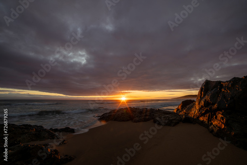 The sun rising amongst the clouds and rocks on Chinamans Beach in Agnes Water, Queensland, Australia