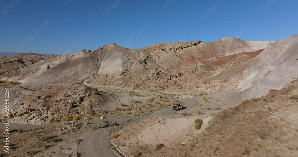 Off-road vehicle crossing Moonscape Overlook in Utah, USA. Aerial backward and blue sky for copy space Off-road vehicle crossing Moonscape Overlook in Utah, USA. Aerial backward and blue sky for copy space