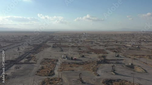 Industrial oil field in Central Valley California. Drone flying forward over pump jacks and working oil drills.