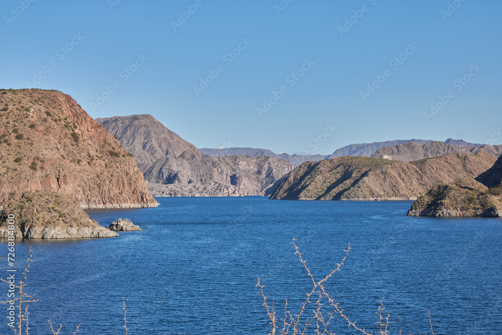 panoramic of the mountains and the blue water of the los reyunos reservoir on a sunny day