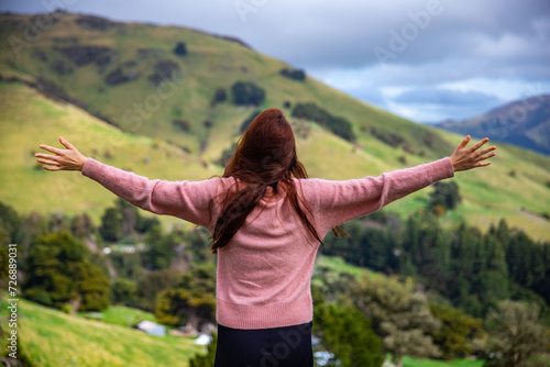 pretty hiker girl enjoys the idyllic landscape of banks peninsula near akaroa, canterbury, new zealand