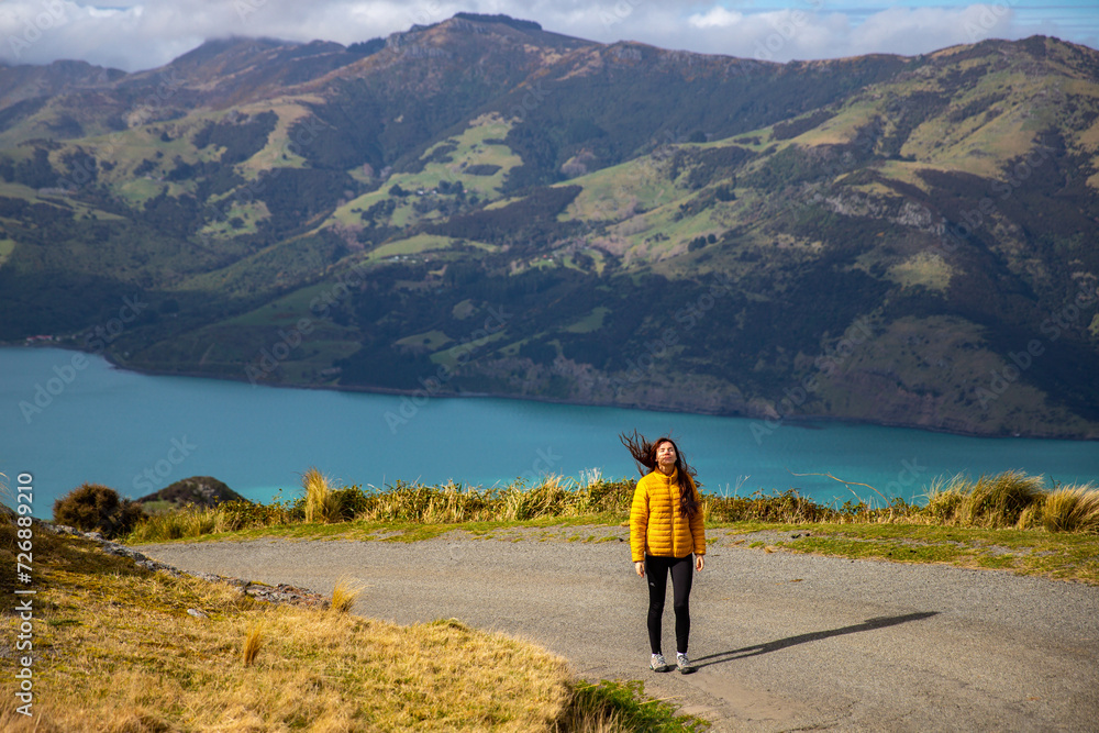 pretty hiker girl enjoys the idyllic landscape of banks peninsula near akaroa, canterbury, new zealand pretty hiker girl enjoys the idyllic landscape of banks peninsula near akaroa, canterbury, new zealand
