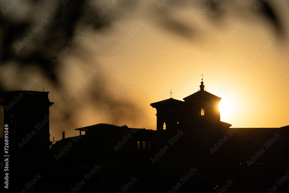 a church with a sun shining behind it and a silhouette