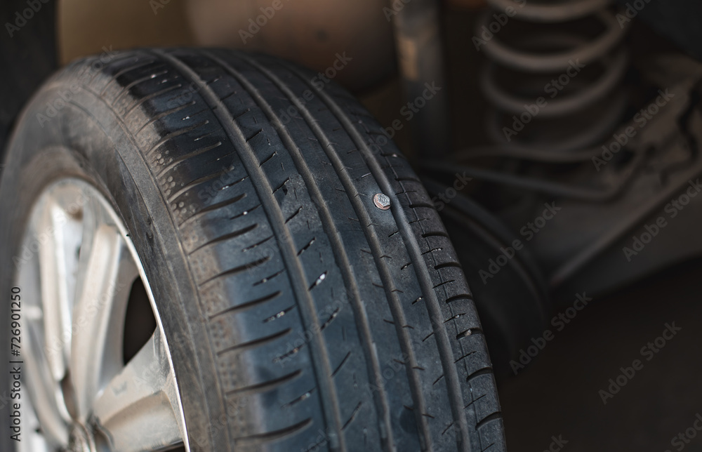 Close-up image of a car tire tread with a screw embedded in it, indicating a puncture risk.. Close-up image of a car tire tread with a screw embedded in it, indicating a puncture risk..