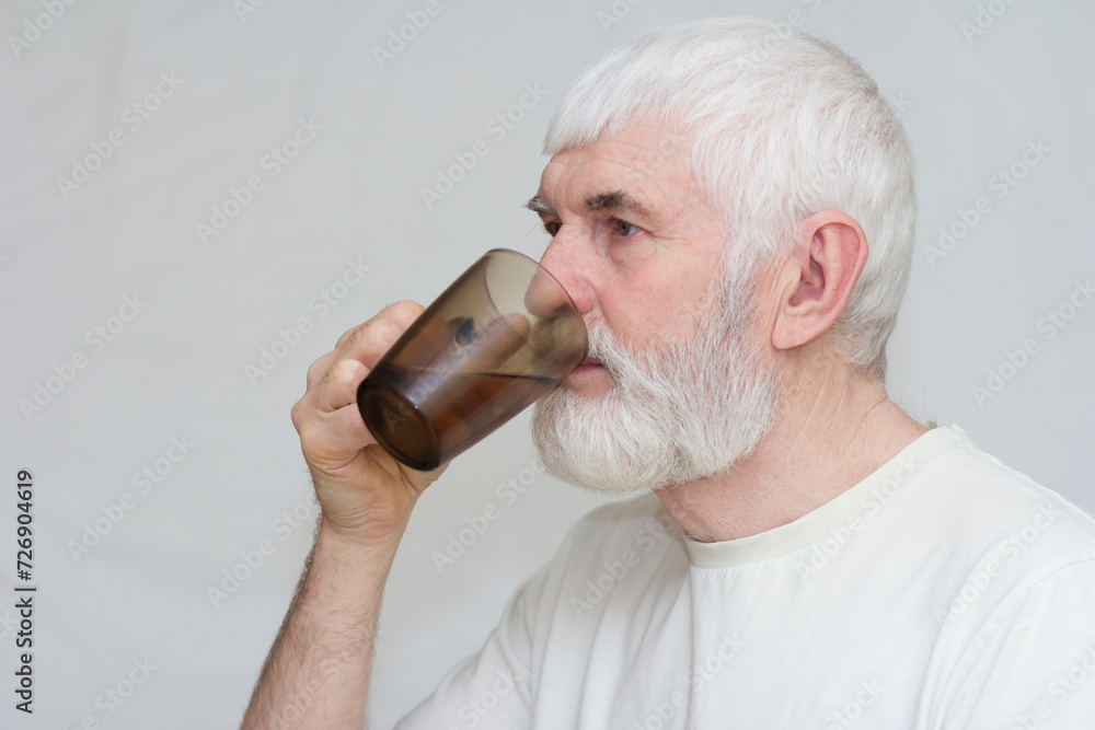 an elderly man with a gray beard drinks clean water from a glass an elderly man with a gray beard drinks clean water from a glass