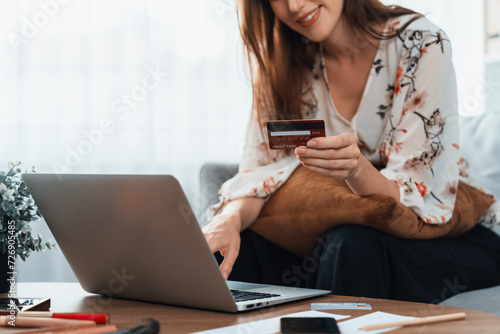 Young happy woman buy product by online shopping at home while ordering items from the internet with credit card online payment system protected by utmost cyber security from online store platform photo