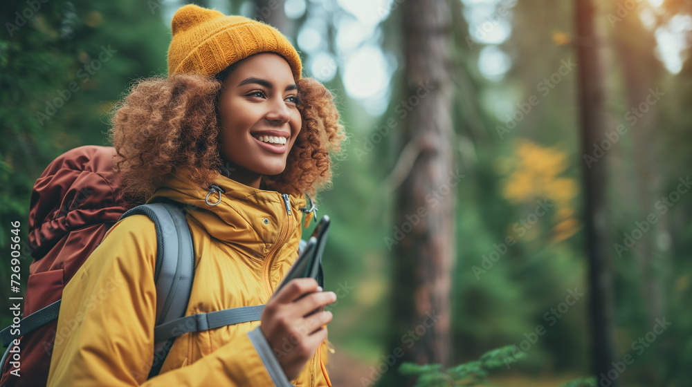 Curly haired woman in winter clothes on hiking trail, holding mobile phone.