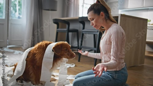 Upset woman punishing dog for mess in apartment close up. Owner scolding pet photo