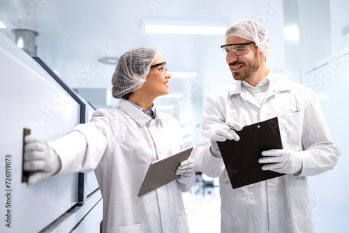 Bild auf Leinwand Pharmaceutical workers in white coat and hairnet checking medicine production inside the factory