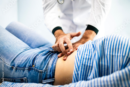 Doctor palpates patient stomach at gastroenterologist clinic. Abdominal medical examination. photo