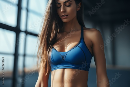 Fit woman in blue sports attire showing toned abdominal muscles - close-up fitness shot