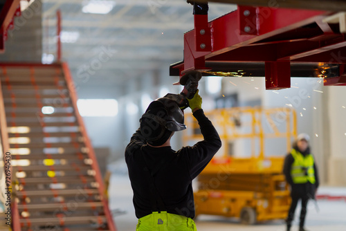 Construction worker with angle grinder and protective face mask and gloves for protection and work safety