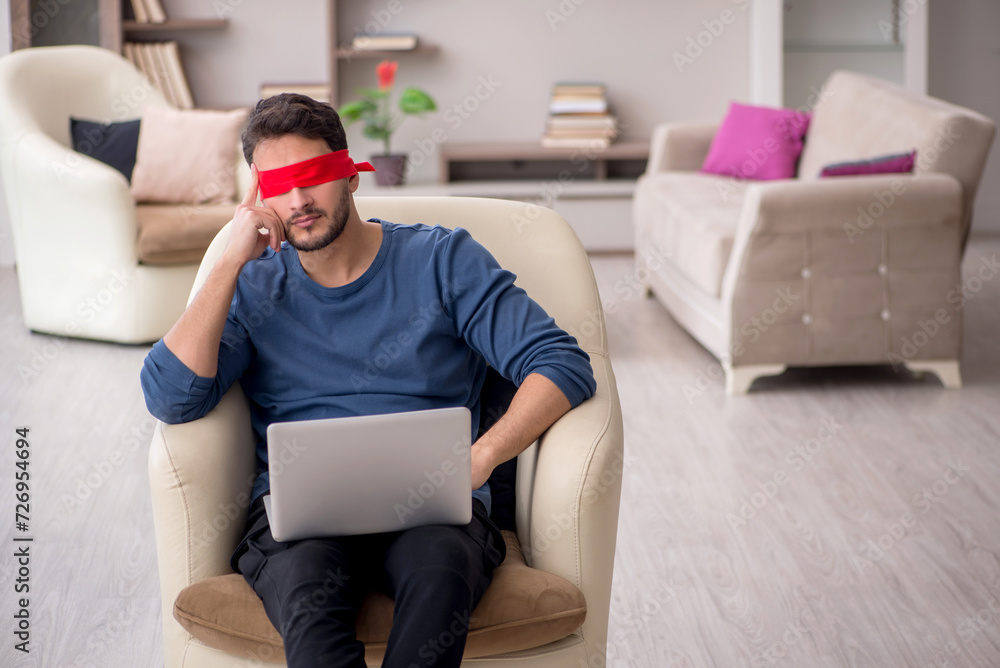 Blindfolded young male freelancer working from home Blindfolded young male freelancer working from home