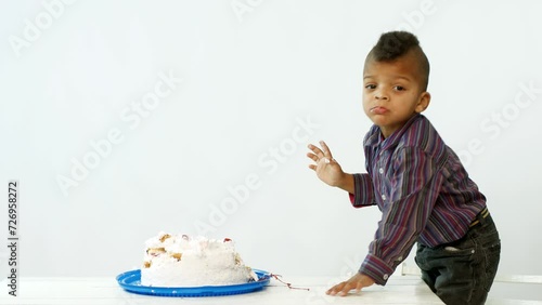 A little dark-skinned boy eats a cake with his hands. Boy sweet-tooth. photo