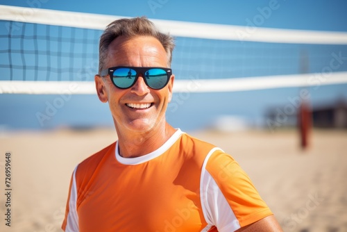 Portrait of happy senior man with sunglasses on beach volleyball court.