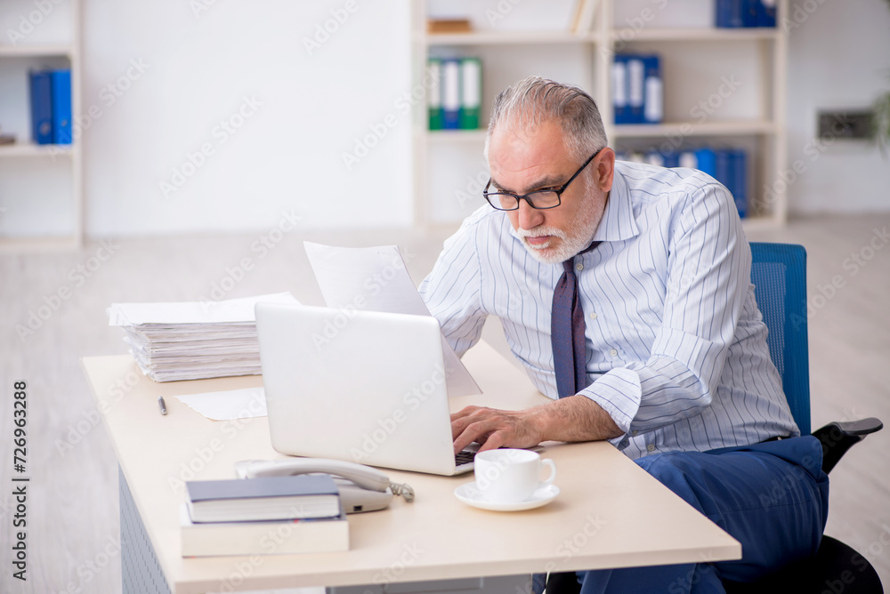 Old male employee working in the office Old male employee working in the office