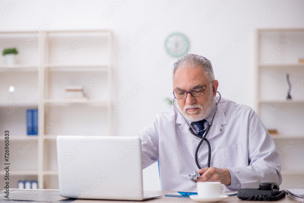 Old male doctor sitting in the clinic Old male doctor sitting in the clinic