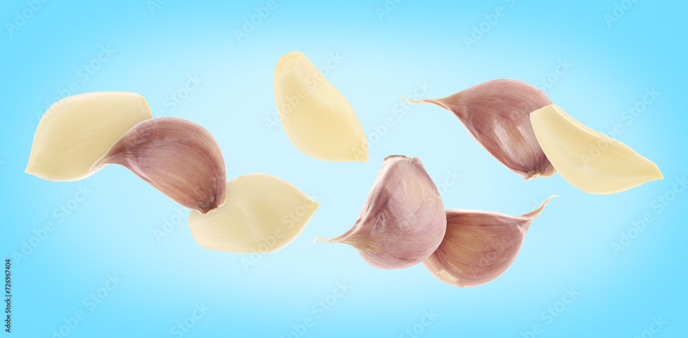 Fresh garlic cloves falling on light blue background, banner design Fresh garlic cloves falling on light blue background, banner design