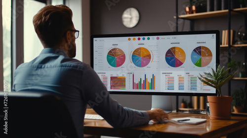 A businessman in front of a monitor showing sales graphs photo