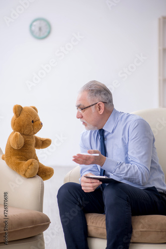 Old male psychologist and soft bear in the room