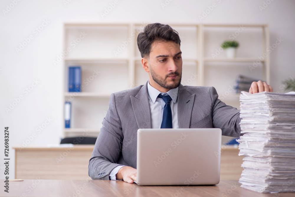 Young male employee and too much work in the office Young male employee and too much work in the office
