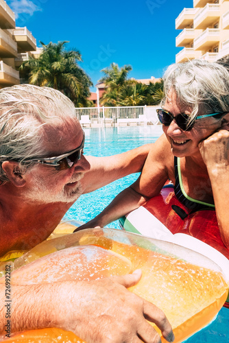 Couple of cheerful and active happy old senior people enjoy the pool in summer vacation holiday leisure activity together - concept of elderly and retired lifestyle with happiness and joy