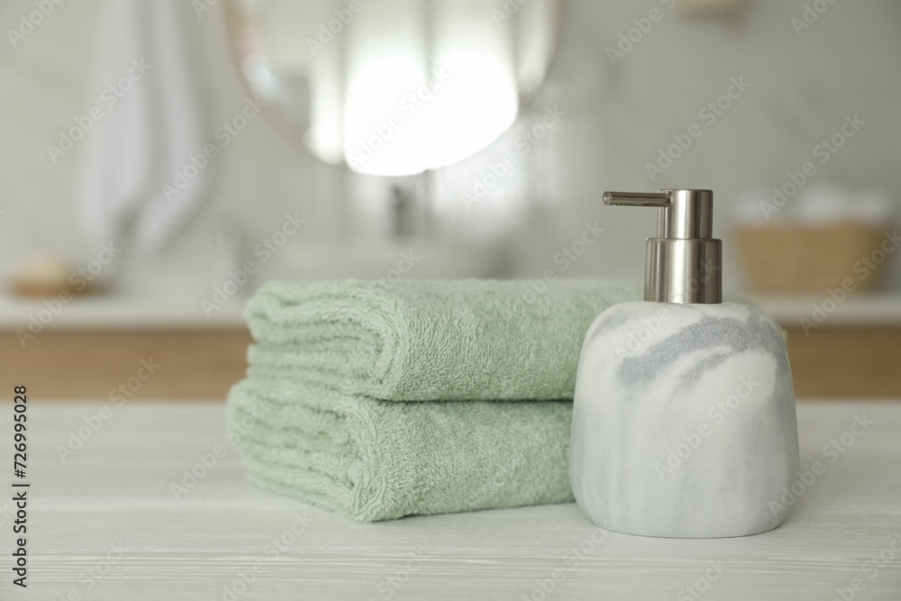 Clean towels and soap dispenser on white wooden table in bathroom Clean towels and soap dispenser on white wooden table in bathroom
