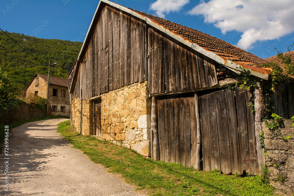 A quiet residential road with agricultural buildings in Martin Brod village in Una National Park. Una-Sana Canton, Federation of Bosnia and Herzegovina. Early September A quiet residential road with agricultural buildings in Martin Brod village in Una National Park. Una-Sana Canton, Federation of Bosnia and Herzegovina. Early September