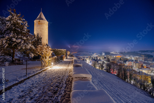 Photo nocturne d'une tour médiéval sur les remparts de la ville de Romont en Suisse