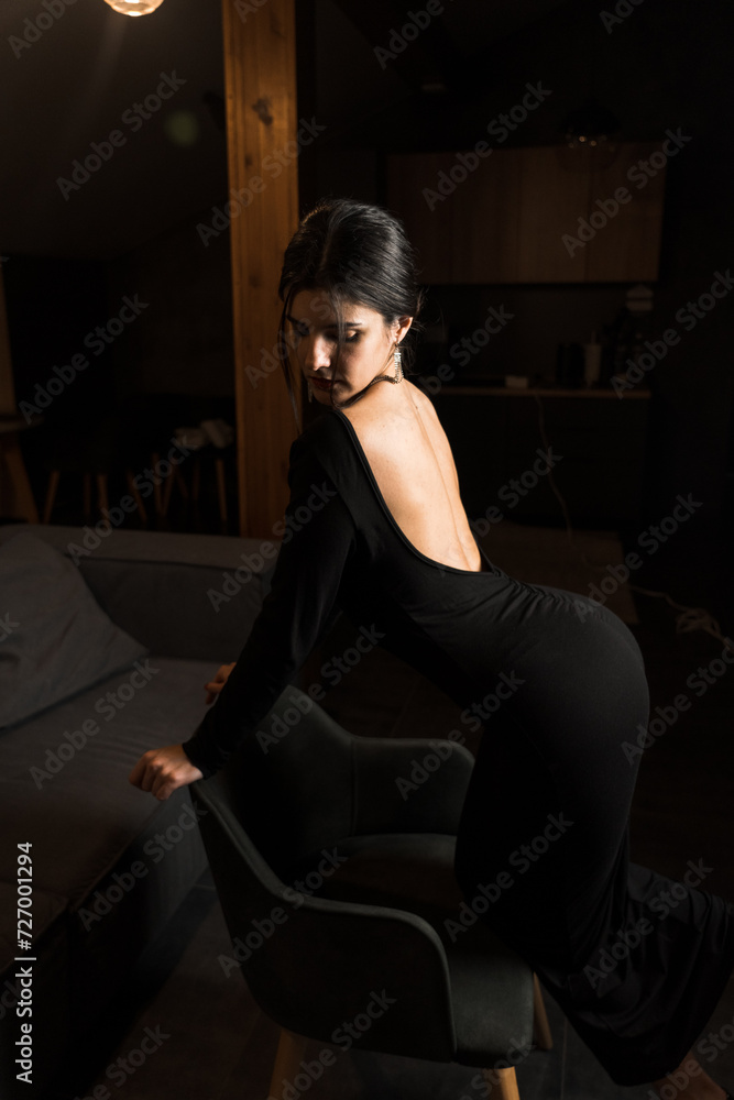 Elegant woman in a black dress posing in an apartment. Fashion shooting concept Elegant woman in a black dress posing in an apartment. Fashion shooting concept