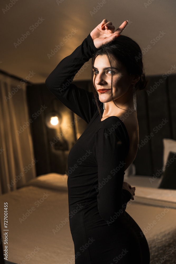 Elegant woman in a black dress posing in an apartment. Fashion shooting concept Elegant woman in a black dress posing in an apartment. Fashion shooting concept