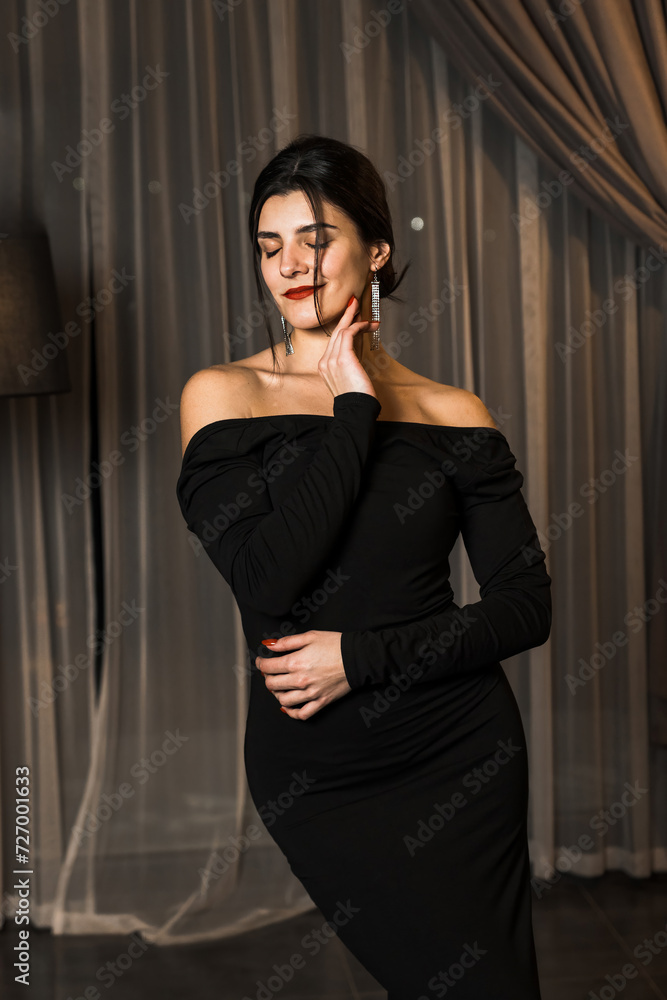 Elegant woman in a black dress posing in an apartment. Fashion shooting concept Elegant woman in a black dress posing in an apartment. Fashion shooting concept