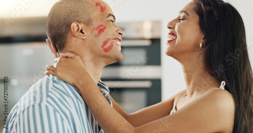 Happy couple  love and kiss with lipstick for fun date and playful at home in intimacy  romance and valentines day. Lover  woman and man in kitchen or house with lip print on cheek for anniversary