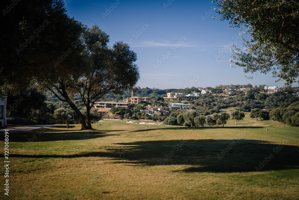 Sotogrante, Spain - January 27, 2024 - serene landscape with a golf course in the foreground, scattered trees, and modern houses on rolling hills in the background under a clear blue sky. Sotogrante, Spain - January 27, 2024 - serene landscape with a golf course in the foreground, scattered trees, and modern houses on rolling hills in the background under a clear blue sky.