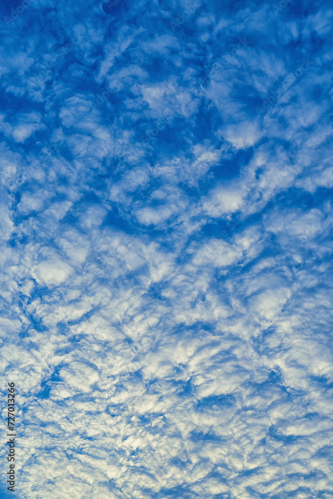 Beautiful waves of clouds against bright blue sky.
