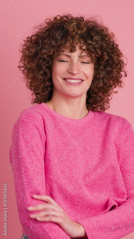 Smiling standing young curly haired woman on pink background. Vertical footage Smiling standing young curly haired woman on pink background. Vertical footage