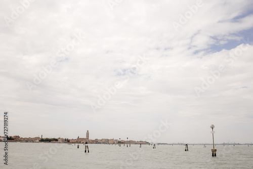 Venice, Italy - View of the Lagoon with City in Distance, Calm Water Surface with Wooden Poles