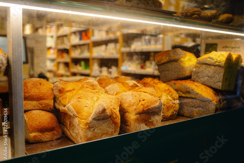 Loaf of bread on a shelf in a bakery with a variety of other breads on shelves in the background