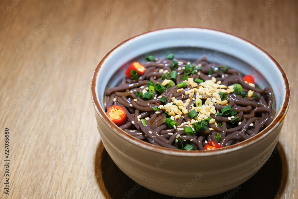 a bowl of Hot and Sour Fern Root Noodles on table. Spicy Chinese Sichuan food a bowl of Hot and Sour Fern Root Noodles on table. Spicy Chinese Sichuan food