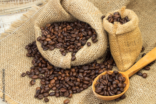 Opened burlap bags, a cup of coffee, scattered whole coffee beans on a white background.