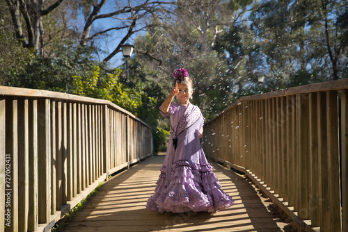 A girl dancing flamenco, playing with soap bubbles, in typical flamenco dress, on a wooden bridge. Concept dance, flamenco, typical Spanish, Seville, Spain.